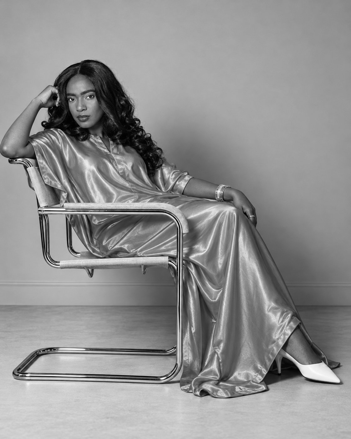 Evelyn Jegede seated in a relaxed studio portrait, photographed in black and white